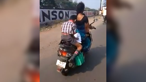 కదిలే స్కూటర్ మీద హోమ్ వర్క్ చేస్తున్న పిల్లాడు