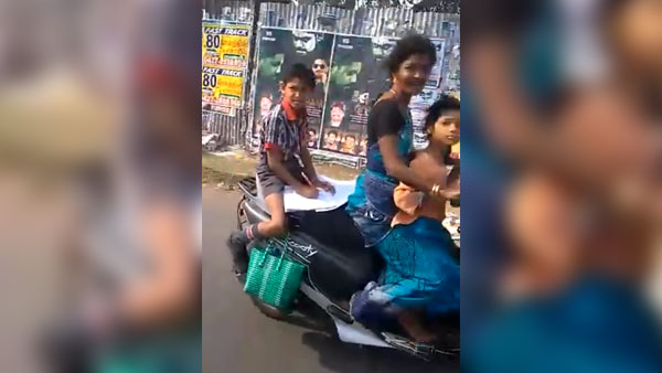 కదిలే స్కూటర్ మీద హోమ్ వర్క్ చేస్తున్న పిల్లాడు